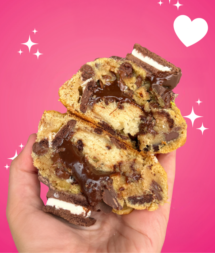 Hand holding a cookie with chocolate filling against a pink background with decorative elements