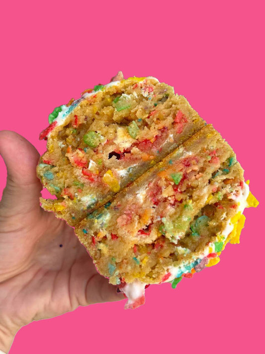 A confetti stuffed cookie being held against a pink background.